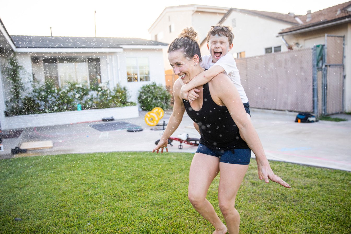 Mom and Son running through sprinklers after workout